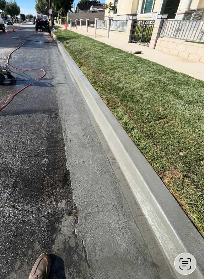Newly finished residential concrete curb and gutter installed along a landscaped street with smooth professional finishing